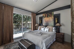 A bedroom with a large bed, a view of the outdoors, and a painting on the wall. - The Happy Cactus (Yzerfontein)