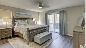 Ein Schlafzimmer mit einem großen Bett, einer Bank, einem Nachttisch, einer Kommode und einem Deckenventilator.