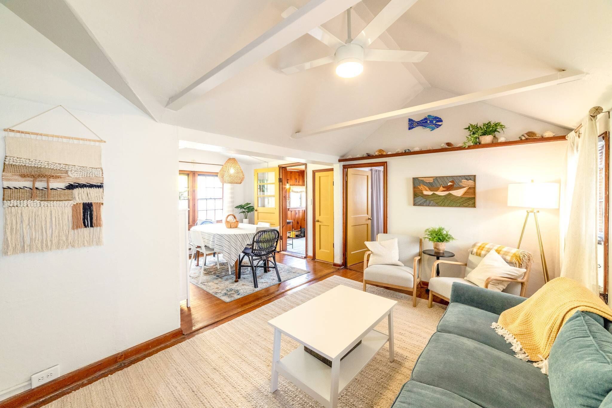 A spacious living room with a ceiling fan, a dining area with a table and chairs, and a cozy seating area with a sofa and armchairs.