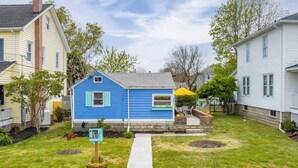 Une maison d’habitation à l’extérieur bleu, avec un jardin devant et un chemin menant à la porte, ainsi qu’une boîte aux lettres.