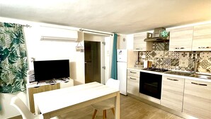 Una cucina moderna con zona pranzo, dotata di televisore a schermo piatto, frigorifero, fornelli e piastrelle decorative a parete.
