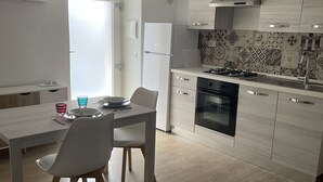 Una cucina moderna con mobili bianchi, piano cottura a gas e forno integrato. C'è un'area pranzo con tavolo e sedie.