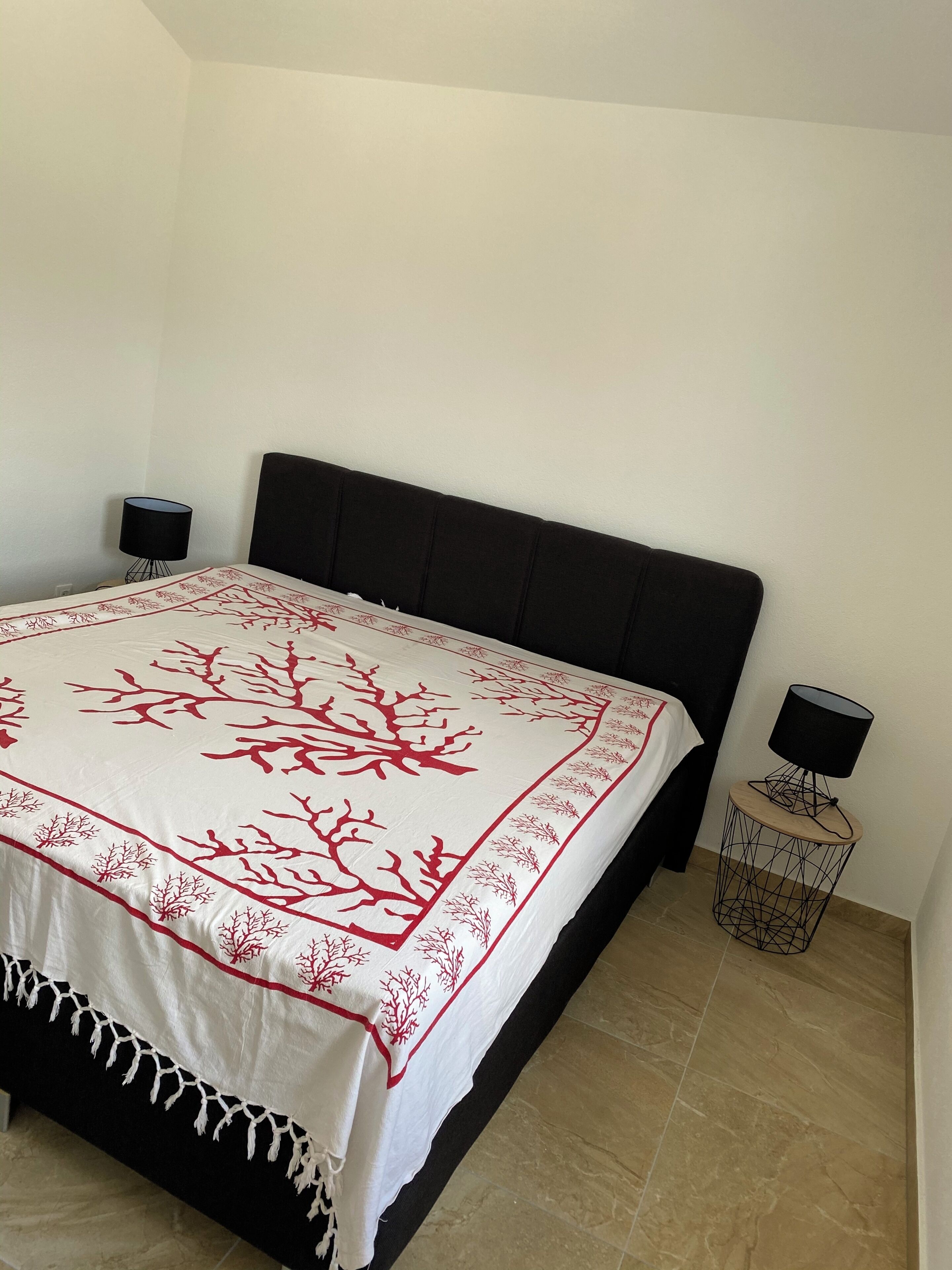 A bedroom with a bed, two bedside lamps, and a small side table.