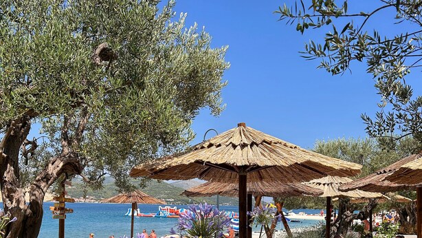 Ambiente sulla spiaggia con posti a sedere all'aperto, ombrelloni e vista sul mare.