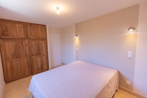 Quarto com cama, guarda-roupa de madeira e luminárias na parede.