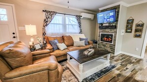 Een woonkamer met een leren bank, een bijzettafeltje en een open haard.