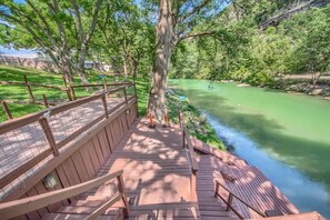 A wooden deck with a railing overlooking a river.