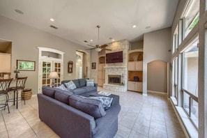 A spacious living room with a gray sectional sofa, a fireplace, and a dining area with a table and chairs.