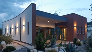 Uma casa moderna com fachada curva, janelas amplas e entrada bem iluminada.
