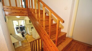 A wooden staircase leading to a second floor with a kitchen area visible in the background.
