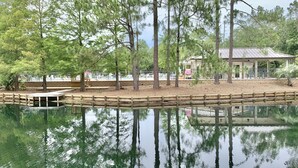 Un étang paisible avec une jetée en bois, entouré d’arbres et agrémenté d’un pavillon.