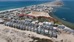 An aerial view of a coastal resort with multiple buildings, a beach, and a pier extending into the ocean. - Tequila Sunrise 4 Bedroom Home by RedAwning (Navarre)
