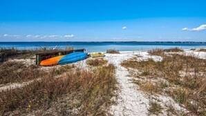 Una playa con un sendero arenoso que lleva al agua, donde hay varias embarcaciones estacionadas.