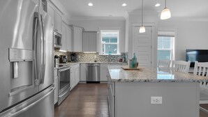 Una cocina moderna con electrodomésticos de acero inoxidable, una encimera de mármol y una isla grande.