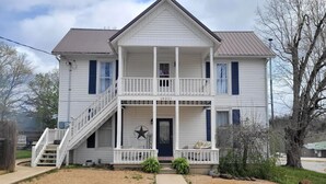 A two-story house with a front porch, a staircase, and a welcome sign.