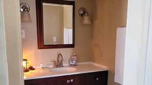 A bathroom with a double vanity, a large mirror, and two wall-mounted lights.