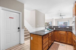 A modern kitchen with wooden cabinets, a granite countertop, and a built-in stove.