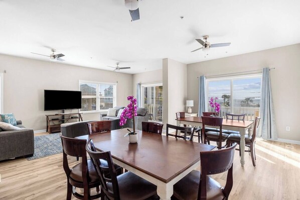 Un salón espacioso con una gran mesa de comedor, asientos cómodos, un televisor de pantalla plana y un balcón con vistas.