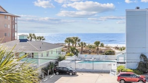 A residential area with a view of the ocean, a swimming pool, and a parked car.