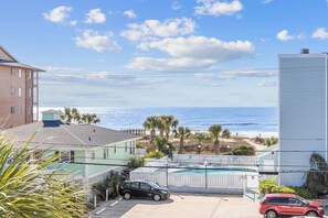 Ett bostadsområde med utsikt över havet, en swimmingpool och en parkerad bil.