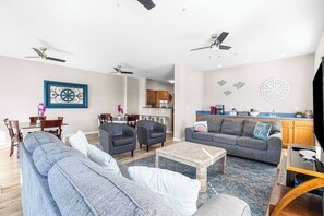A modern living room with a sofa, armchairs, a coffee table, and a dining area with chairs and a table. - Ocean Breeze- 13 Bds- Game Room- Slps 20- 3 Decks (North Myrtle Beach)