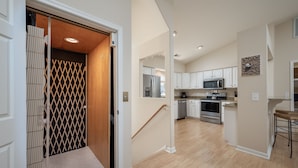 A modern kitchen with white cabinets, stainless steel appliances, and a wooden floor. - Condo with elevator and POND VIEWS! - 12 Pondview Lane (Lewes)