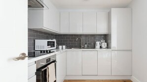 Una cucina moderna con mobili bianchi, un forno a microonde, un bollitore e un lavandino.