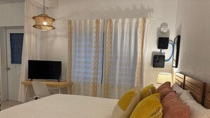 Ein Hotelzimmer mit einem Bett, einem Schreibtisch mit Fernseher, einer Lampe und Vorhängen mit geometrischem Muster.