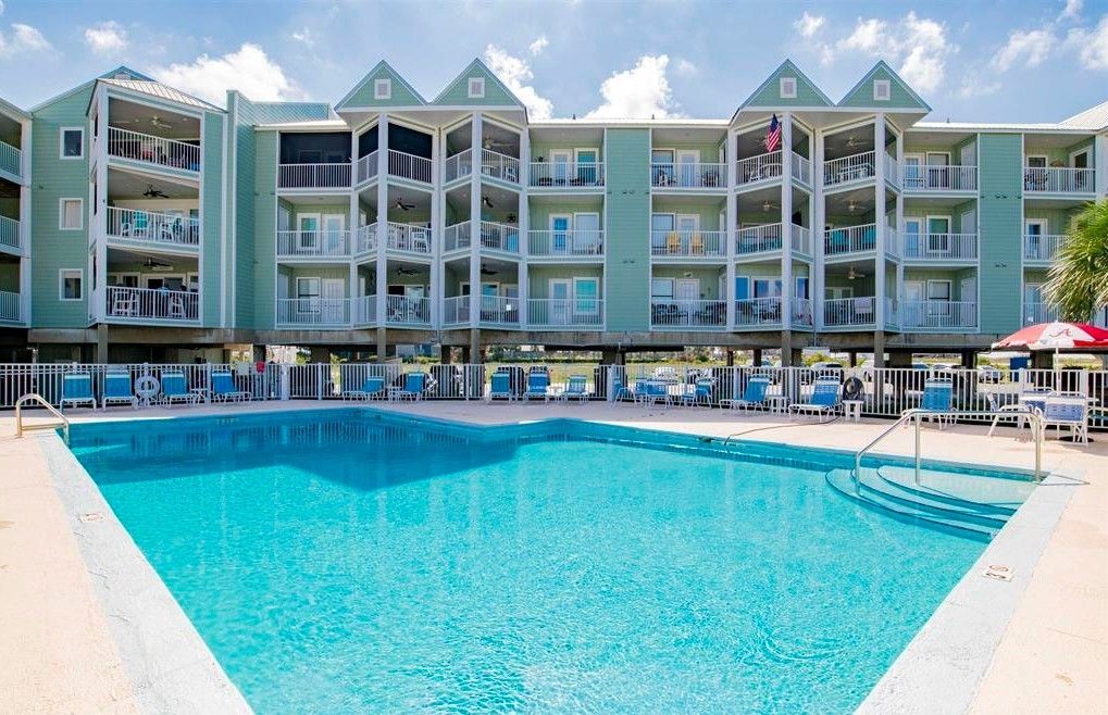 Ein Hotel mit Schwimmbad, mehreren Balkonen und einer Flagge.