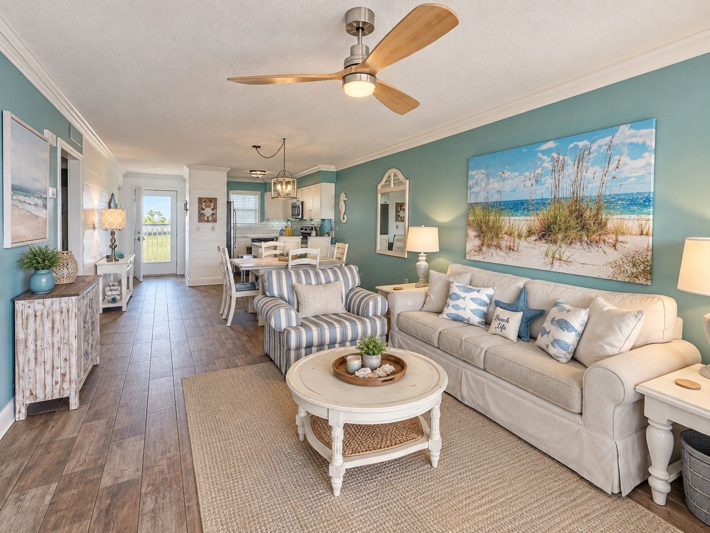 A living room with a sofa, coffee table, and a painting of a beach scene.