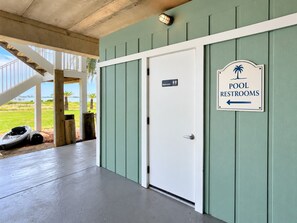 Ein Gebäudeeingang mit Schild für Pooltoiletten, einer Treppe und Außenbestuhlung.