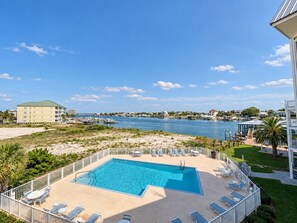 A pool area with lounge chairs and a view of a marina.