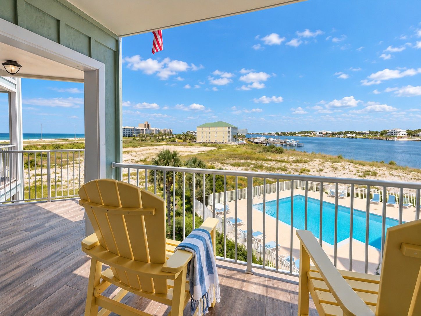 A balcony with a view of a beach and a swimming pool.