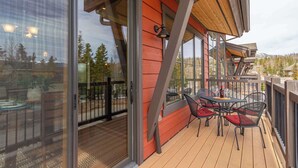 Eine Holzterrasse mit Außenmöbeln und großen Fenstern.