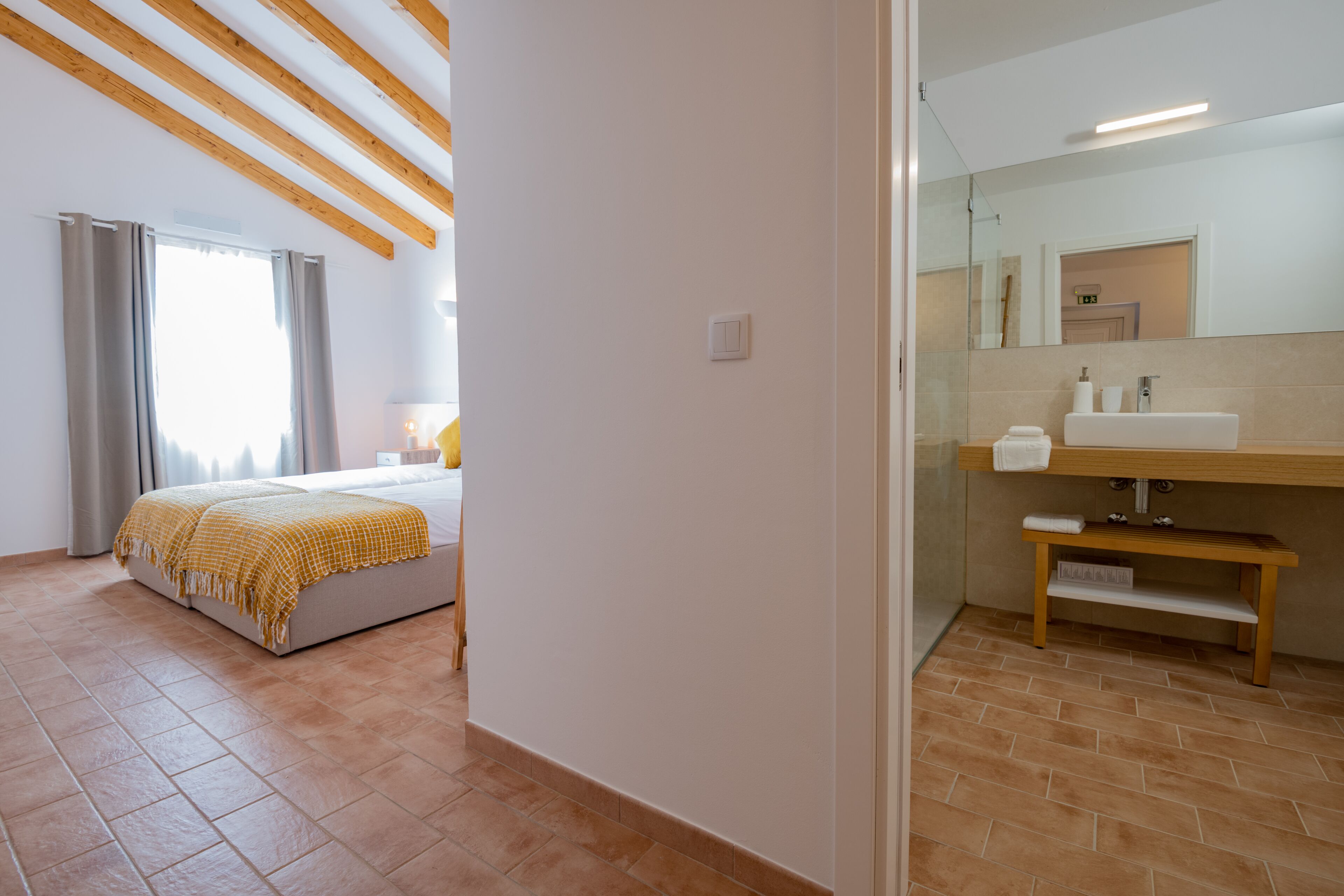 A bedroom with a bed, a bedside table, and a window with curtains.