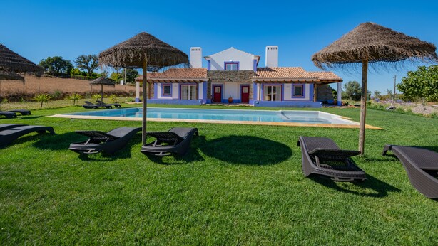 Ein Poolbereich mit Liegestühlen und einem Haus im Hintergrund.