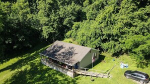 A single-story building with a porch, surrounded by a well-maintained lawn and dense trees.
