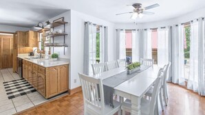 Une cuisine moderne avec des meubles en bois, un îlot central et un coin repas comprenant des chaises blanches et une table.