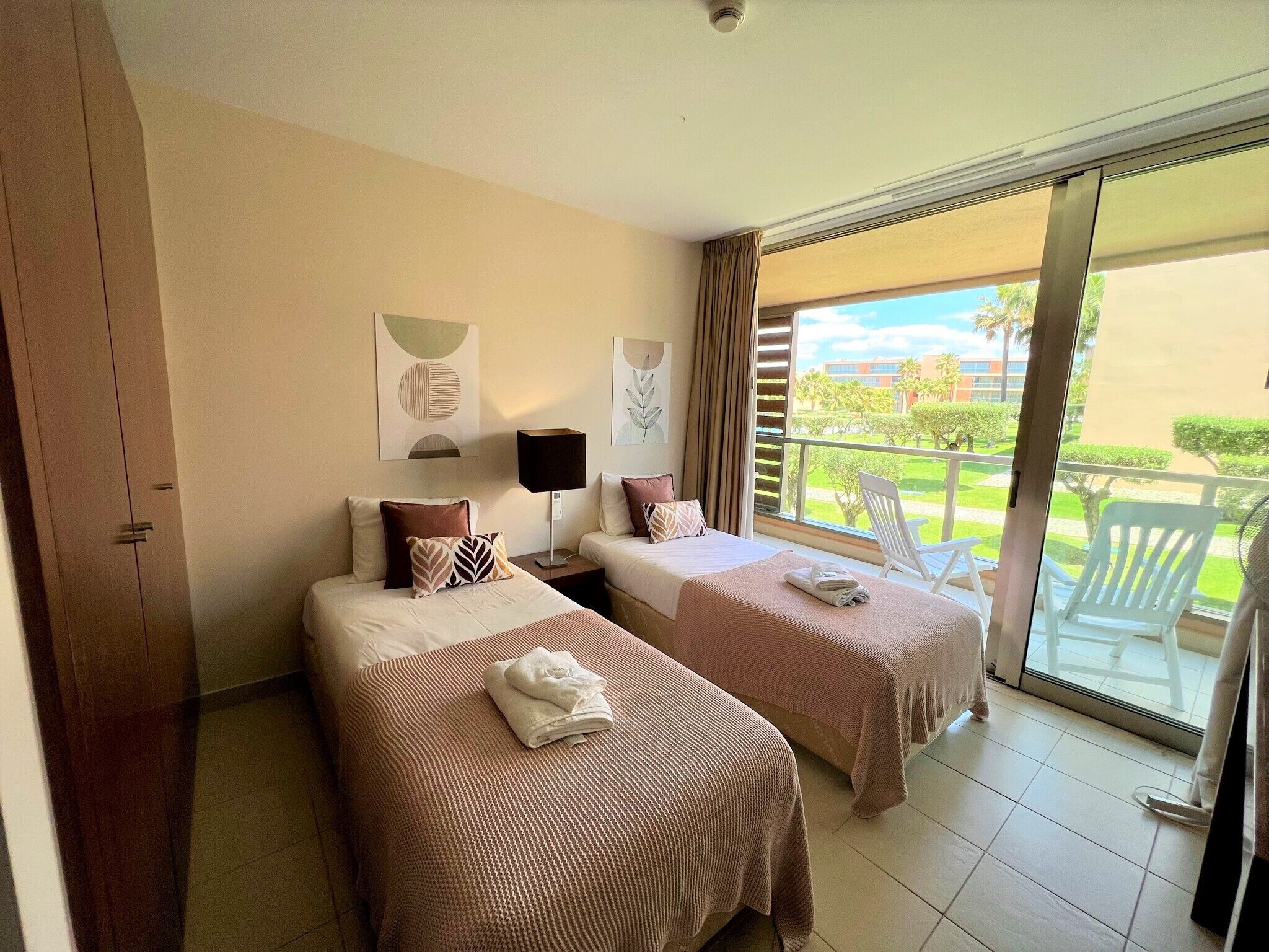 Habitación de hotel con dos camas, un balcón y vistas al exterior.