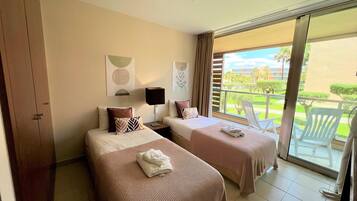 Habitación de hotel con dos camas, un balcón y vistas al exterior.