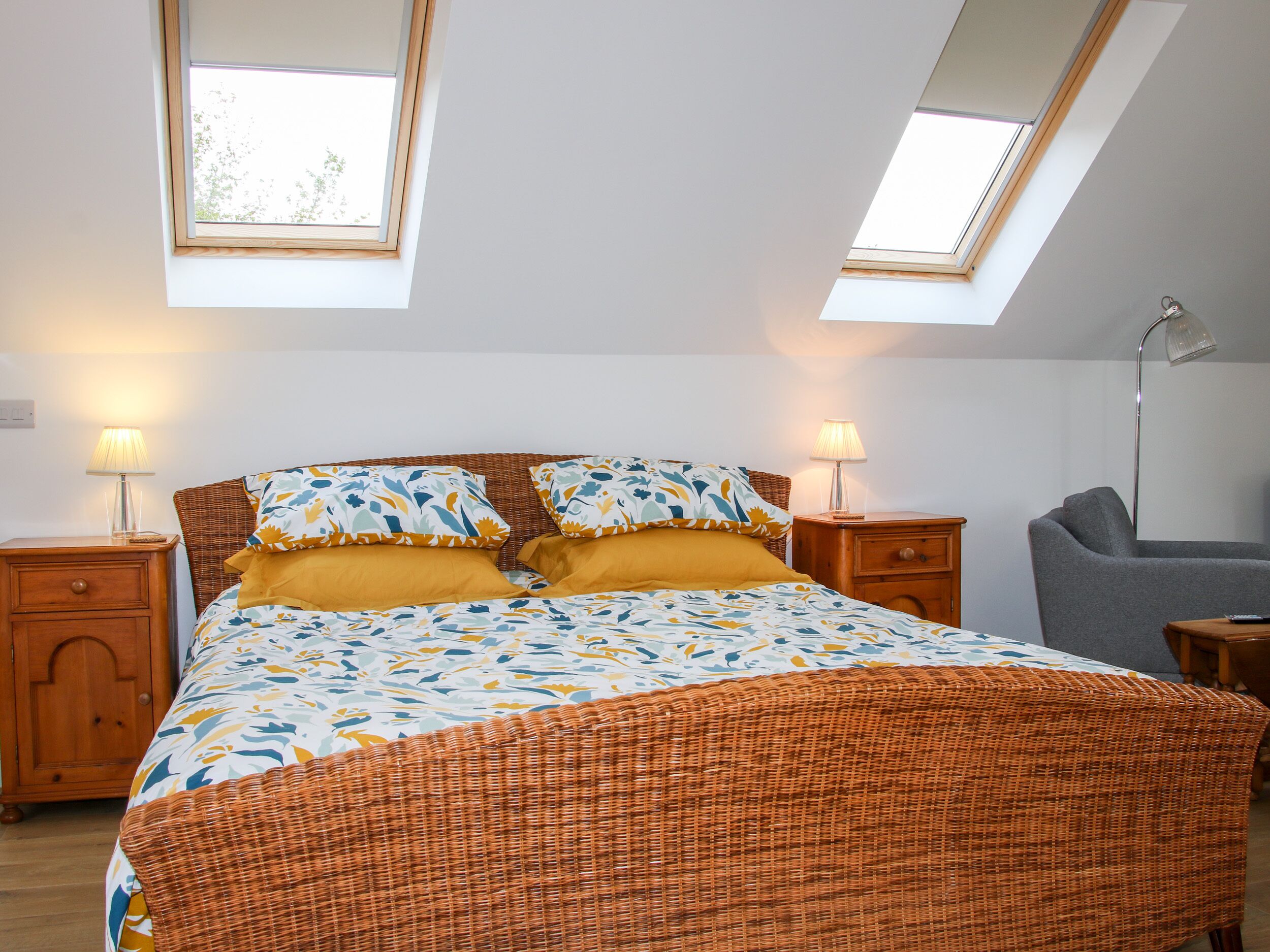 A bedroom with a bed, two bedside tables, a lamp, and a chair.