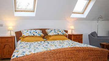 A bedroom with a bed, two bedside tables, a lamp, and a chair.