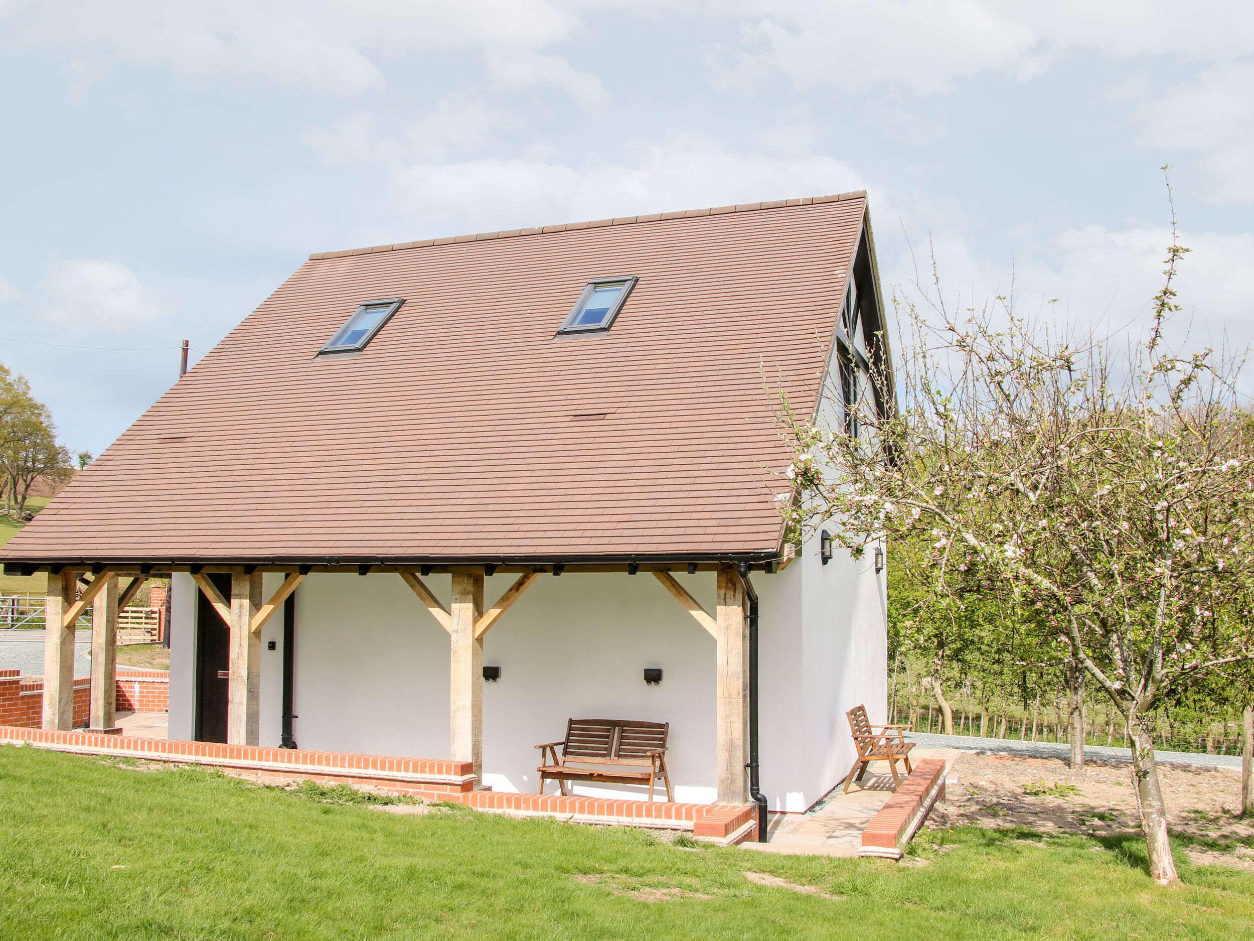 A single-story house with a sloped roof, two windows, and a porch with a bench.