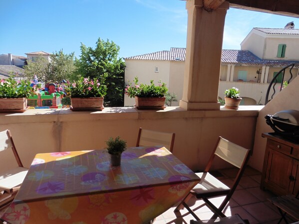 A patio with a table, chairs, and potted plants.