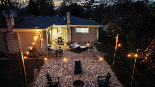 A backyard with a patio area, outdoor seating, and a fire pit. - Spacious, Elegant Home w/ Cozy Backyard! (Troy)