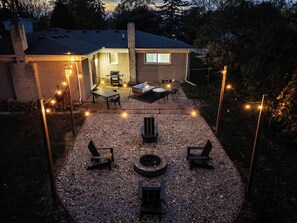 Ein Garten mit Terrasse, Sitzgelegenheiten und einer Feuerstelle.