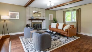 A living room with a fireplace, a sofa, a coffee table, and a patterned rug. - Spacious, Elegant Home w/ Cozy Backyard! (Troy)