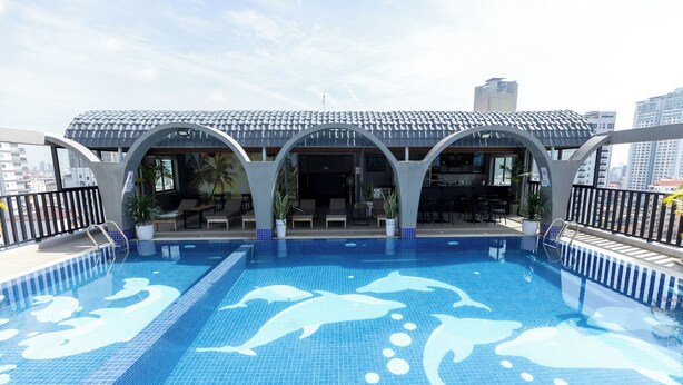 A rooftop pool with dolphin designs, a covered seating area, and a view of the city skyline. - The ONRA Hotel (Phnom Penh)
