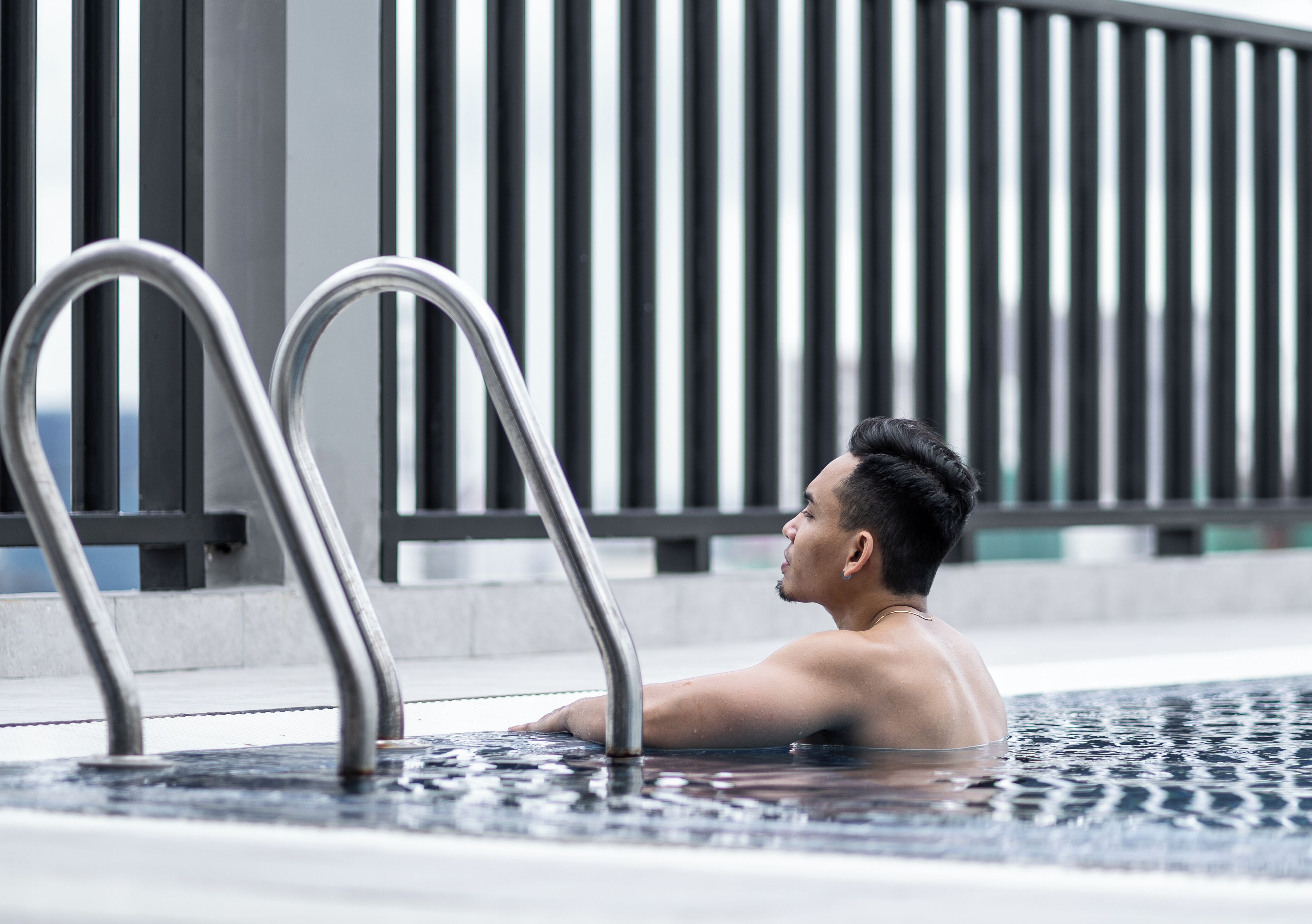A man in a hot tub with metal railings in the background.