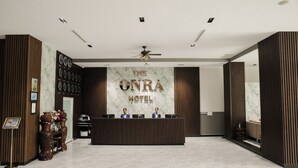 A reception area with a marble wall, wooden paneling, and a reception desk. - The ONRA Hotel (Phnom Penh)